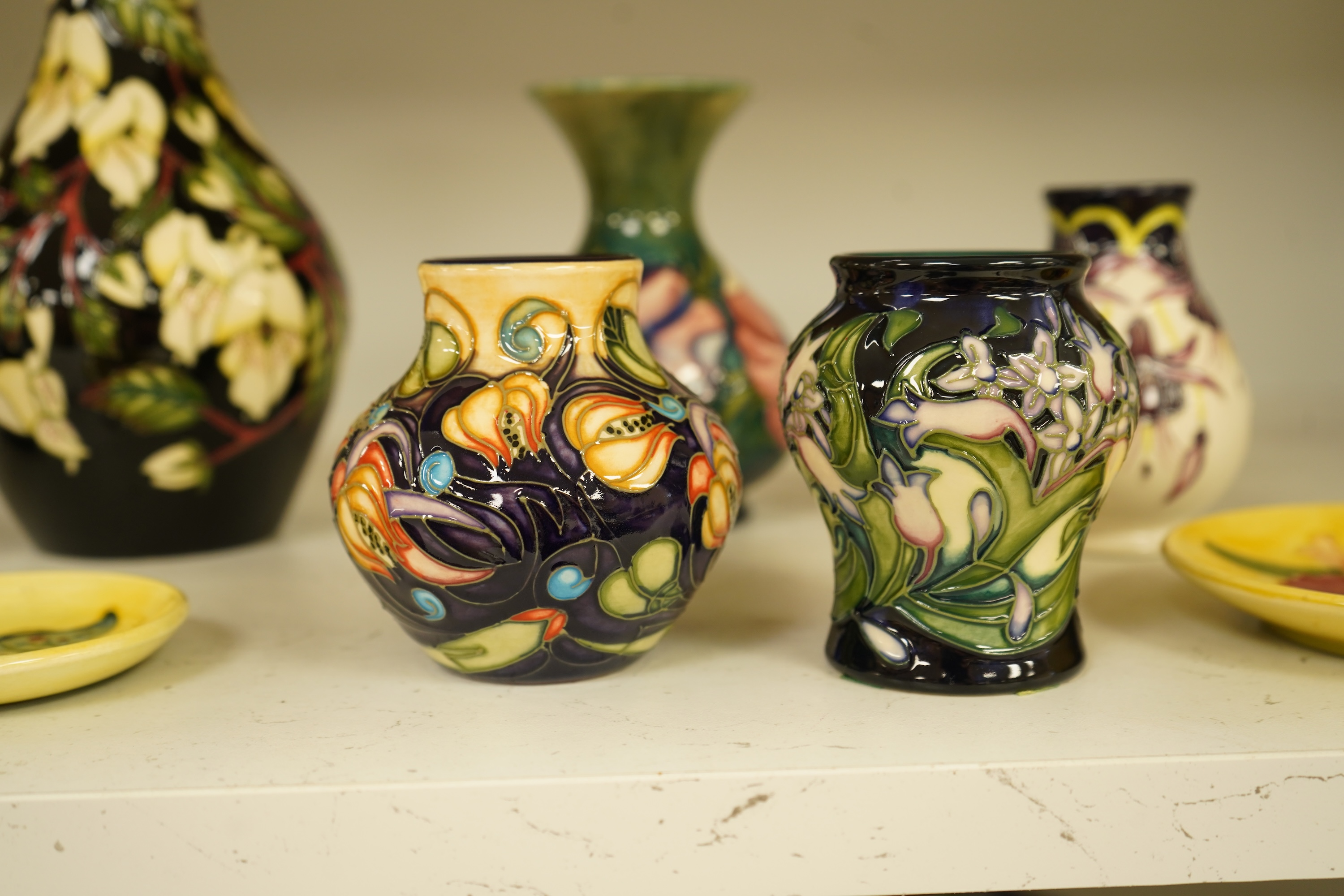 A collection of modern Moorcroft to include a mountain gold pattern vase, two pin dishes and a Hibiscus pattern candlestick, largest 20cm high